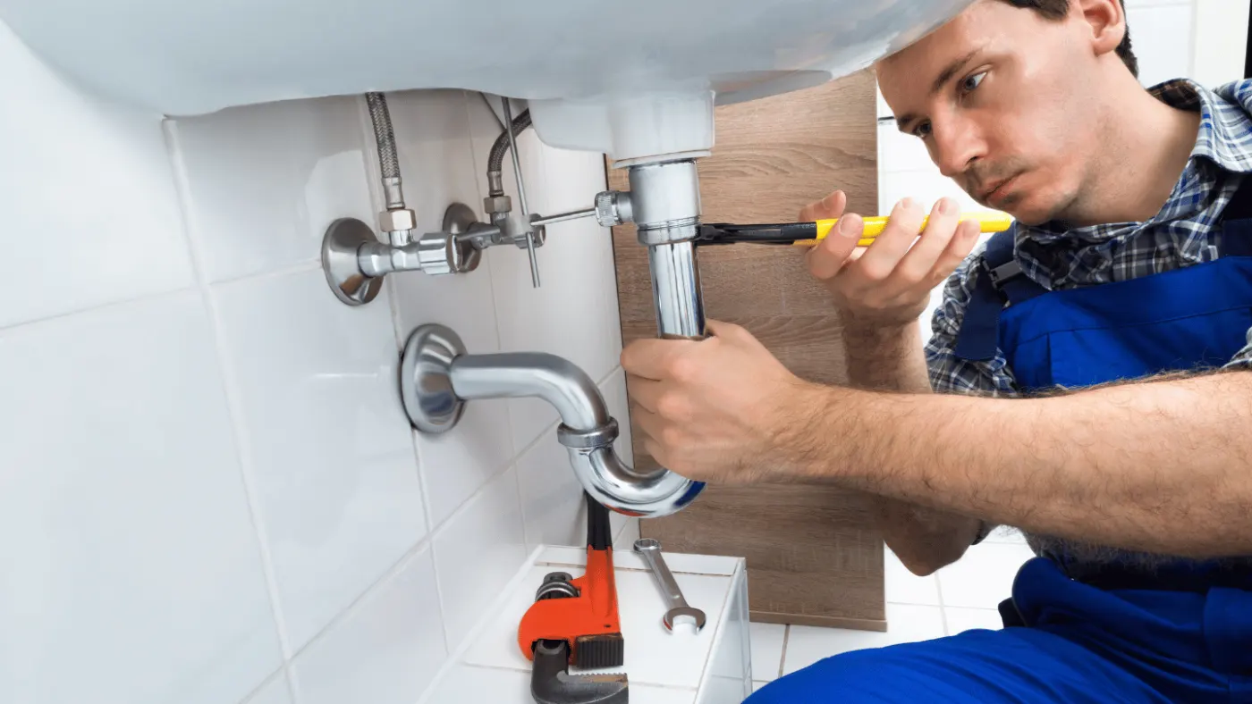 Plombier en intervention sous un lavabo